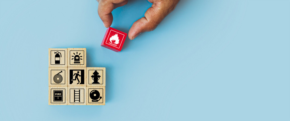 Hand choose cube wooden block stack with fire icon and door exit sing or fire escape with prevent icon and fire extinguisher and emergency prevention or protection symbol for safety and rescue.